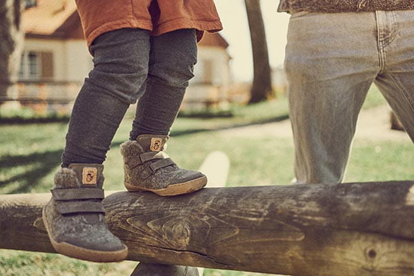 kind balanciert auf einem klettergerüst in kinder winter barfußschuhen
