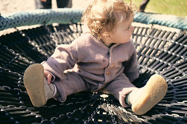 kleines mädchen trägt lauflernschuhe und sitzt in einer schaukel