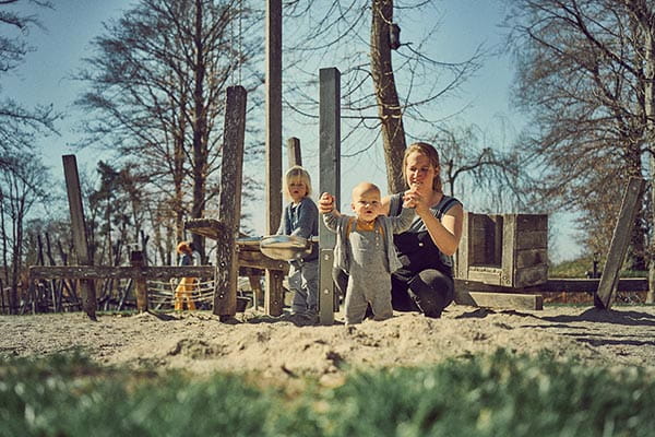 mutter trägt barfußschuh sneaker und spielt mit ihren kindern im sandkasten