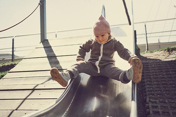kind sitzt auf einer rutsche mit barfußschuhen für den winter