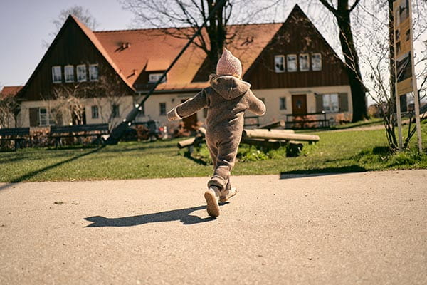 mädchen läuft mit kinder barfußschuhen zum spielplatz